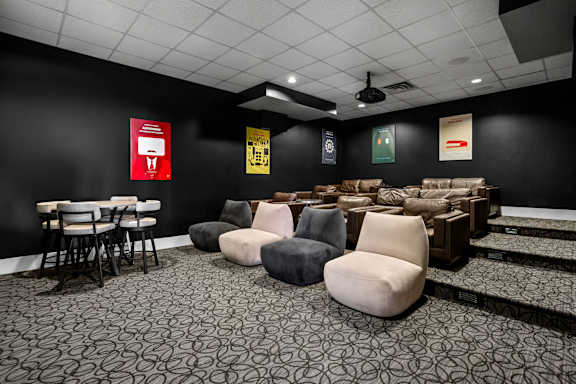 A room with black walls and a patterned carpet with several chairs and a table.
