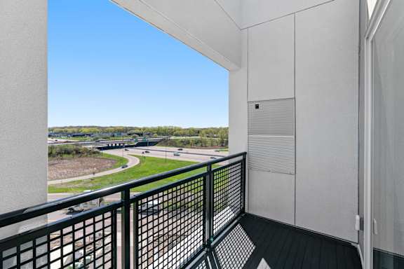 a balcony with a view of a freeway and a blue sky at The Mera, St Louis Park, MN 55426