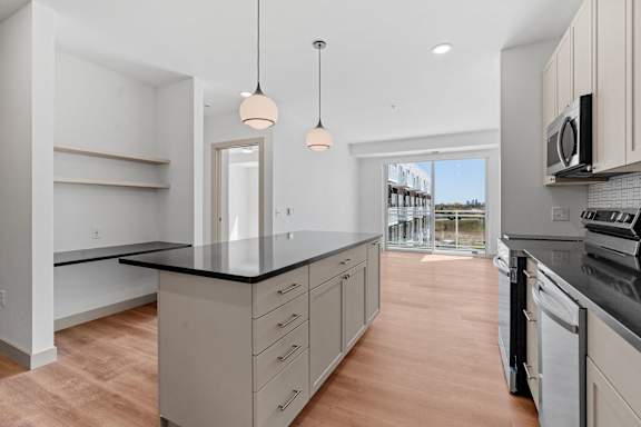 a kitchen with a large island and a door to a balcony at The Mera, St Louis Park, MN