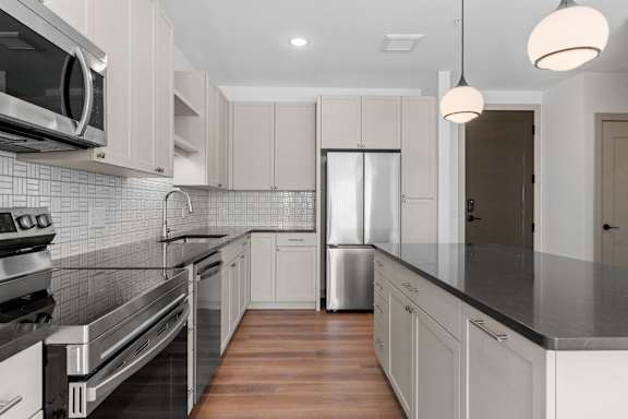a kitchen with black counter tops and white cabinets at The Mera, St Louis Park, MN