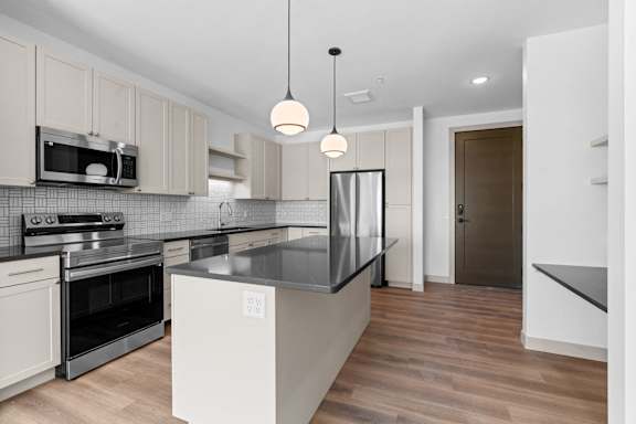 a renovated kitchen with white cabinets and black counter tops at The Mera, St Louis Park, 55426