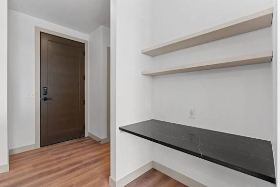 a living room with white walls and a black bench and a door at The Mera, St Louis Park, 55426