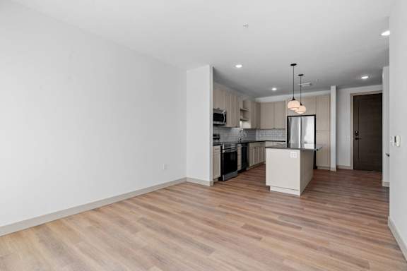 a renovated living room and kitchen with wood floors and white walls at The Mera, St Louis Park, 55426
