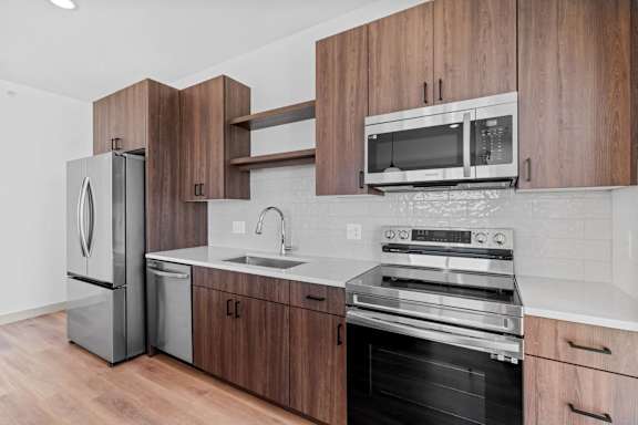 a kitchen with stainless steel appliances and wooden cabinets at The Mera, St Louis Park Minnesota