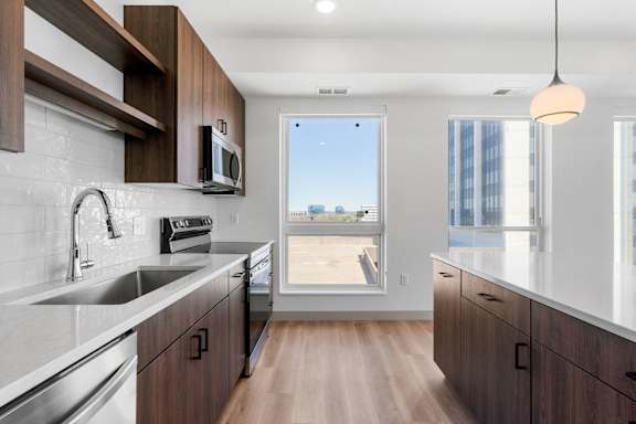 a kitchen with wooden cabinets and a sink and a window at The Mera, St Louis Park Minnesota