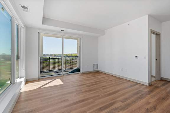 an empty living room with wood floors and a balcony at The Mera, St Louis Park
