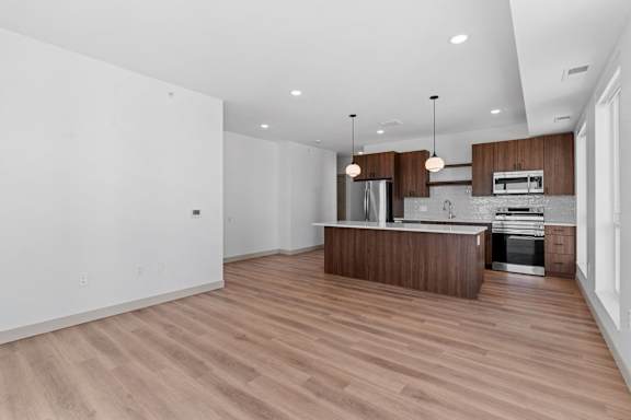 an empty living room and kitchen with wood floors and white walls at The Mera, St Louis Park