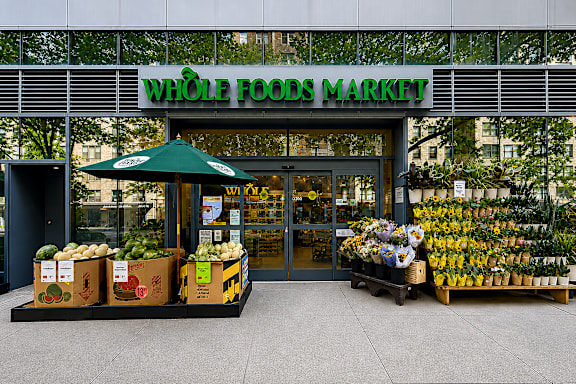 A Whole Foods Market storefront with produce displayed outside.