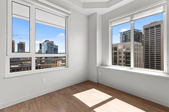 an empty room with three windows and a city view