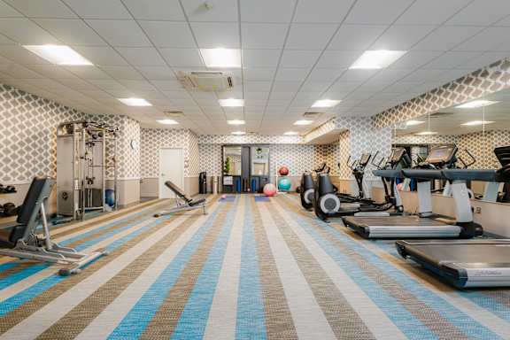 A gym with a variety of equipment including treadmills, weights, and exercise machines.