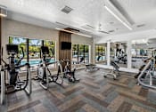 Thumbnail 2 of 4 - A gym with a variety of exercise equipment including treadmills, stationary bikes, and weight machines.