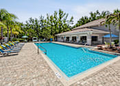 Thumbnail 4 of 4 - A large outdoor swimming pool surrounded by palm trees and a building.