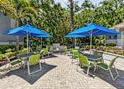 Thumbnail 3 of 4 - A patio with blue umbrellas and green chairs.