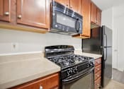 Thumbnail 2 of 8 - A kitchen with a black refrigerator, black stove, and black microwave above a counter with a beige countertop.