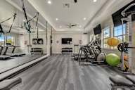 A spacious gym with a variety of equipment and a ceiling fan.