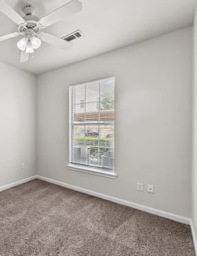 an empty room with carpet and a ceiling fan