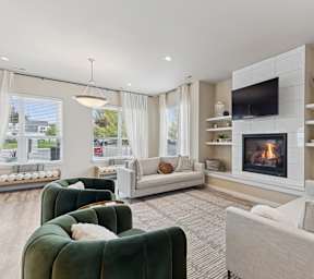 A living room with a grey couch, a coffee table, a fireplace, and a flat screen TV mounted on the wall. at Woodland Meadows Apartments, Post Falls, ID, 20032