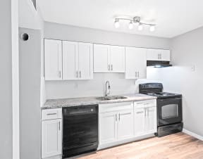 an empty kitchen with white cabinets and black appliances at Uphill Flats, Georgia, 30032