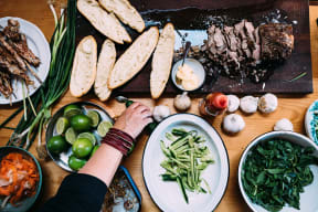 a person preparing food on a table with plates of food
