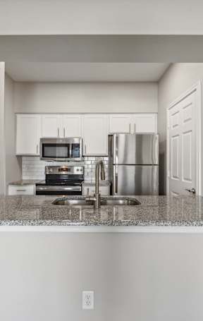 a kitchen with white cabinets and stainless appliances