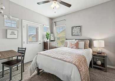 A bedroom with a bed, nightstand, and chair.