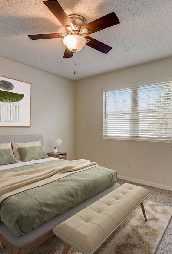 A bedroom with a bed, a ceiling fan, and a painting on the wall.