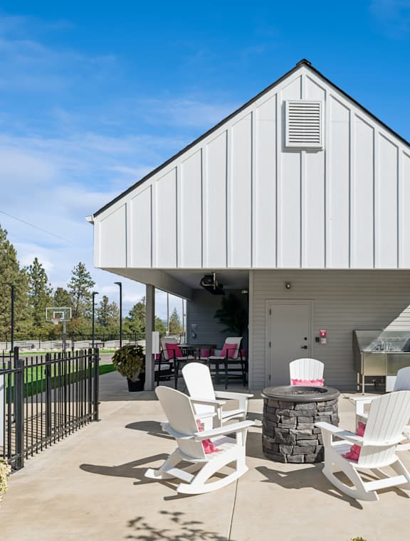A white building with a black fence and patio furniture in front.