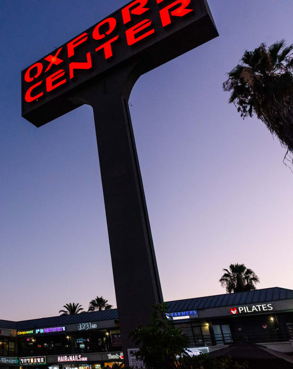 a large illuminated sign in front of a shopping center at night