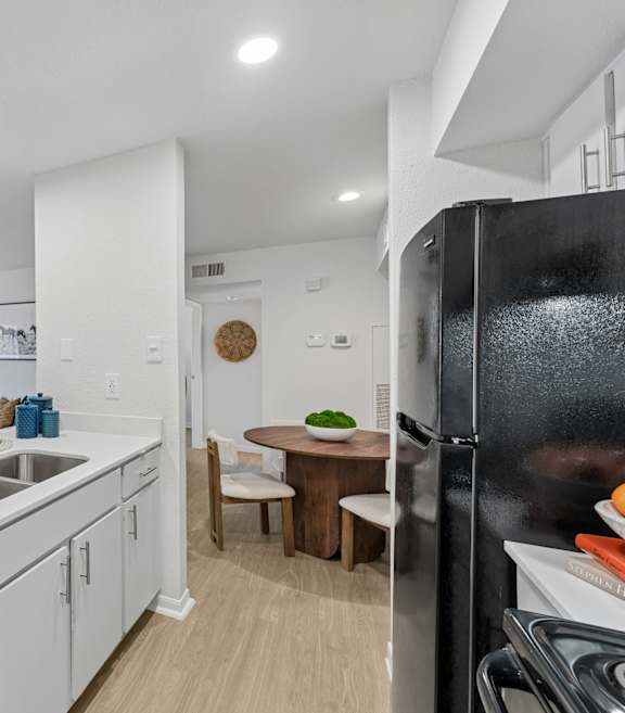 A modern kitchen with white cabinets and a black refrigerator.