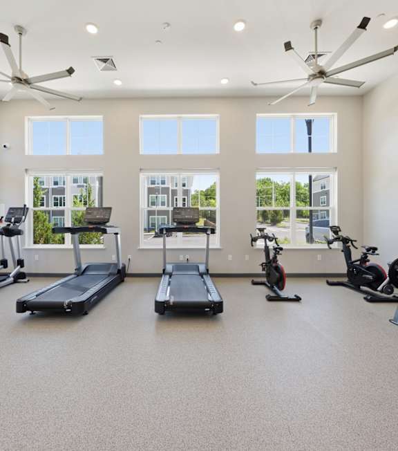 A spacious gym with a variety of exercise equipment and a ceiling fan.