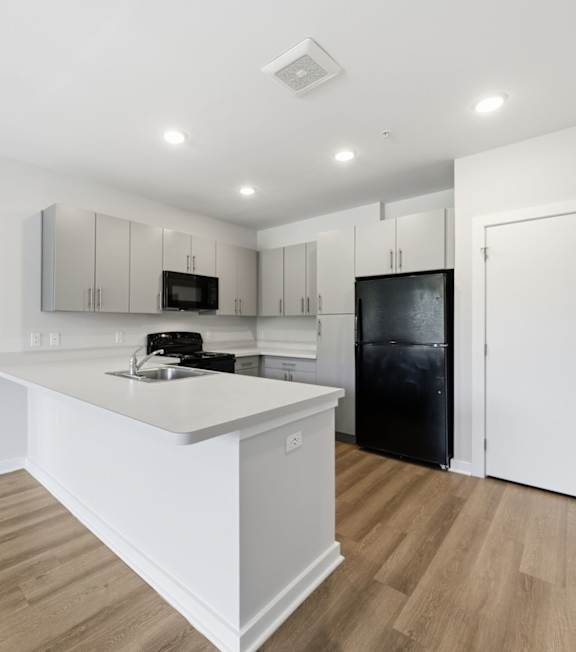 A room with a ceiling fan and a counter with cabinets.
