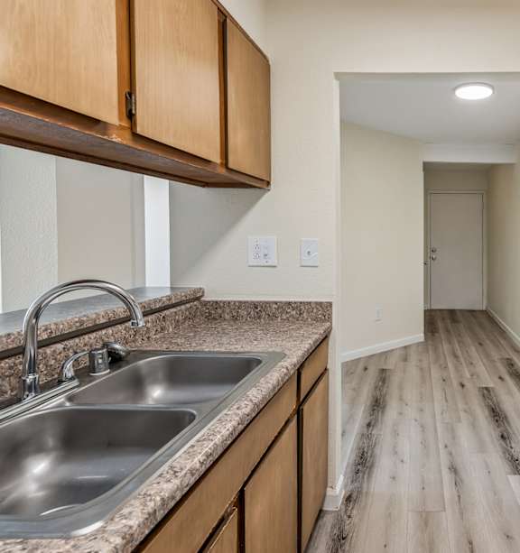 A kitchen with a stove, sink, and wooden cabinets.