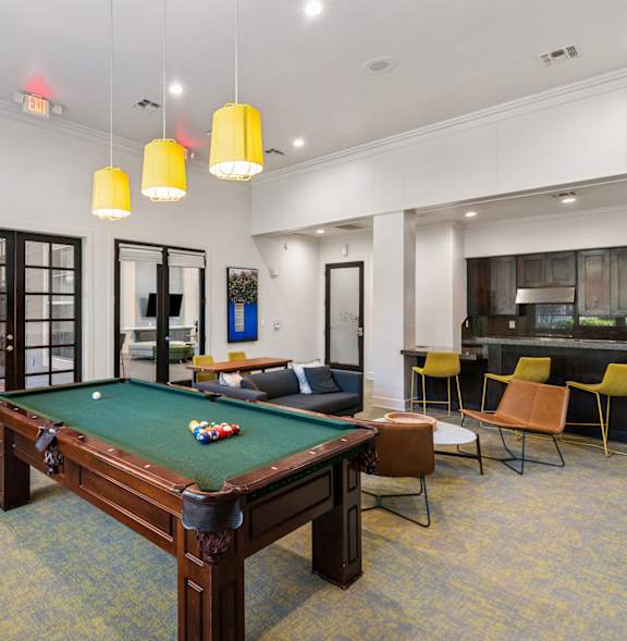 A pool table is surrounded by yellow chairs in a room.