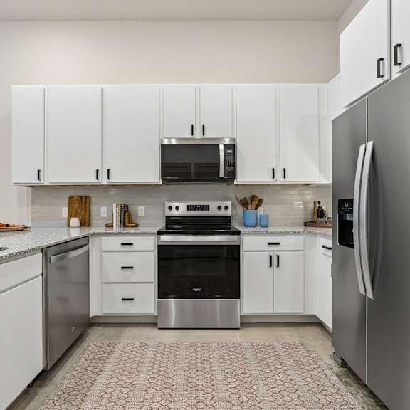 A modern kitchen with white cabinets and stainless steel appliances.