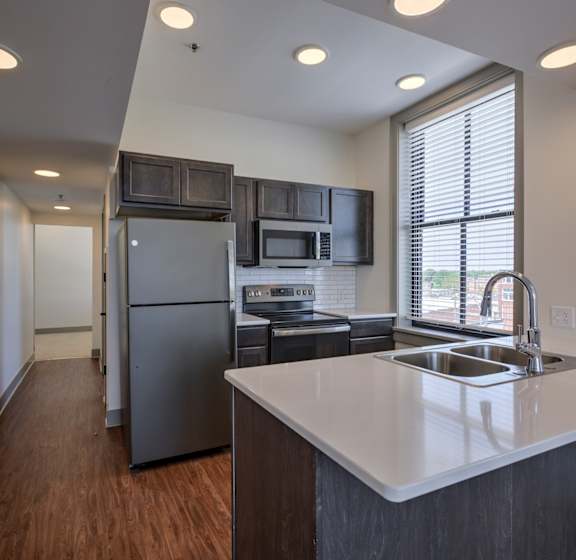 A kitchen with a white counter top and stainless steel appliances.