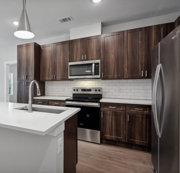 an empty kitchen with wooden cabinets and a white counter top at The Virginia, Seguin, 78155