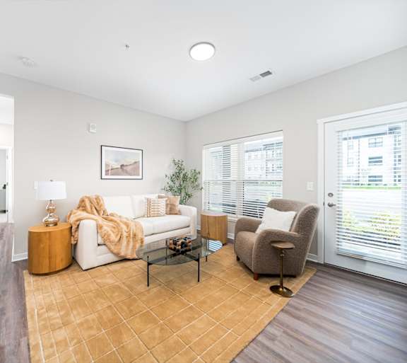 A living room with a white couch, a wooden coffee table, and a brown rug.