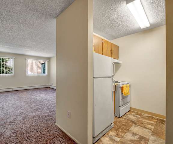 A kitchen with white appliances, light counter, and spacious wooden cabinets at Lakewood Heights. 