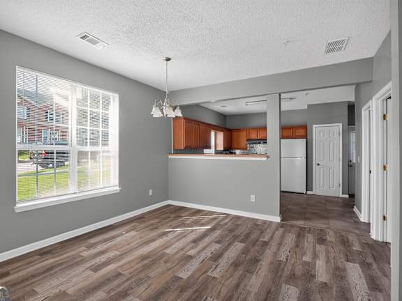 A room with wooden flooring and a kitchen area in the background.