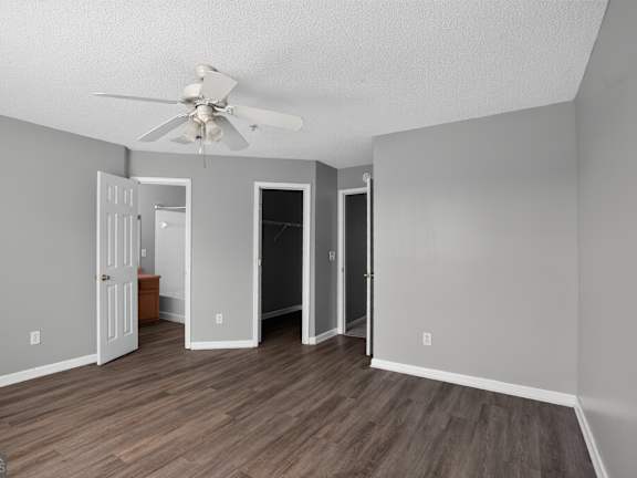A room with a ceiling fan and three doors.