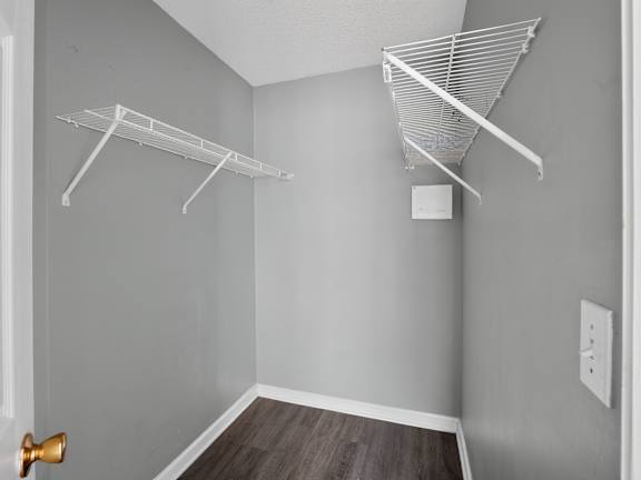 A room with a white door, grey walls and a white shelf.