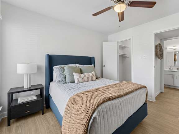 A bedroom with a bed, nightstand, and a ceiling fan.