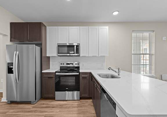 A modern kitchen with a refrigerator, microwave, oven, and sink.