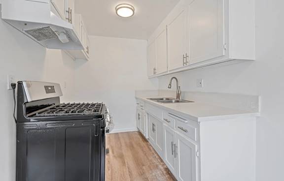 A modern kitchen with white cabinets and a black dishwasher.