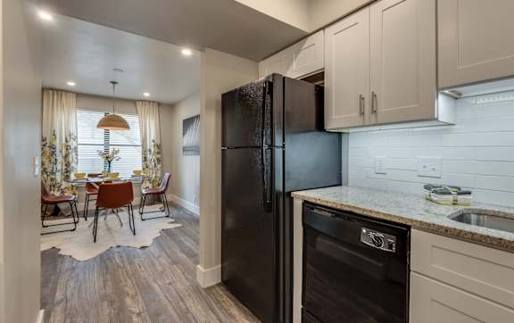 the kitchen and dining room of a home with a black refrigerator