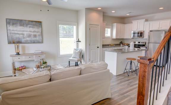 a kitchen and living room with white cabinets and a granite counter top