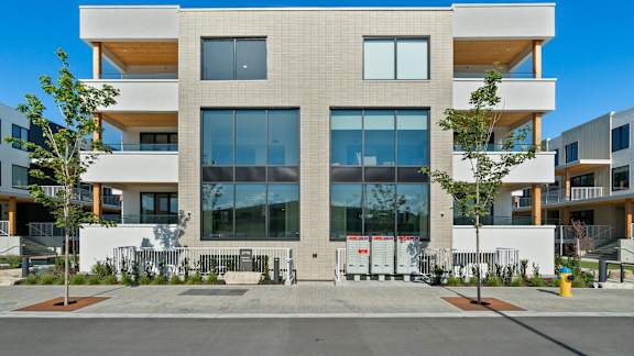 an apartment building with large windows and a sidewalk