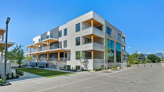 a large white apartment building with balconies and a lawn