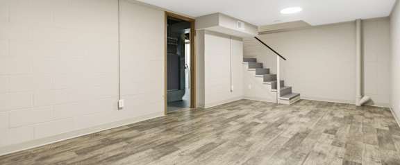 A room with a wooden floor and a staircase.