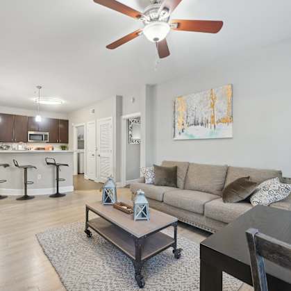 A living room with a couch, coffee table, and a ceiling fan.